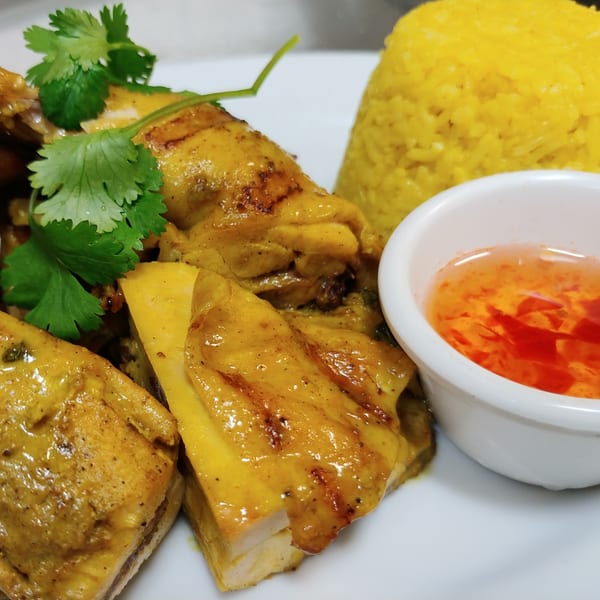 Siri Thai Cuisine's yellow curry chicken with rice and sweet chili sauce on a white plate.