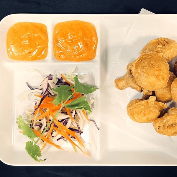 Crispy fried chicken nuggets, two orange dipping sauces, and a fresh cabbage and carrot salad.