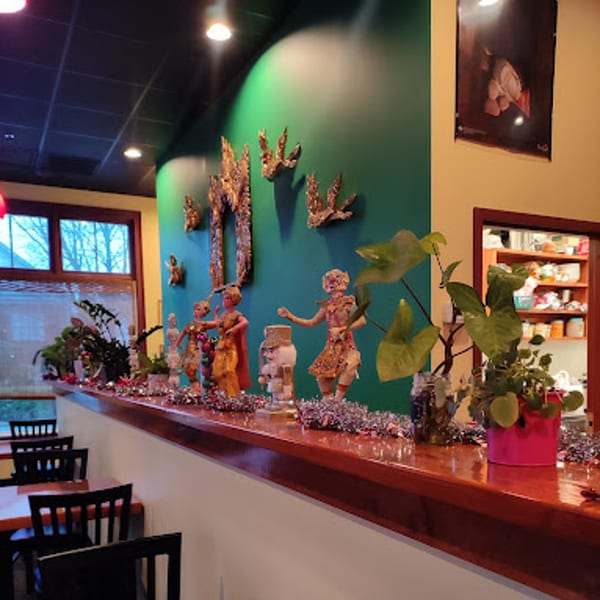 Interior of Siri Thai Cuisine, featuring Thai decor, plants, and dining tables with black chairs.