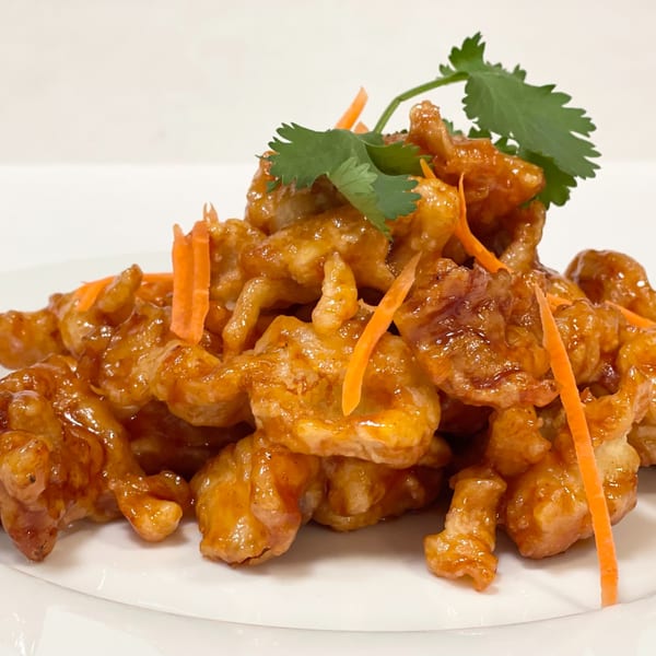 Siri Thai Cuisine's sweet and sour chicken, garnished with cilantro and shredded carrots on a white plate.